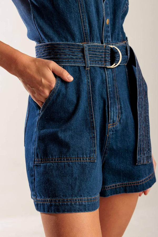A denim romper featuring a round neckline, button down, cuffed sleeve, self belt, and pockets.