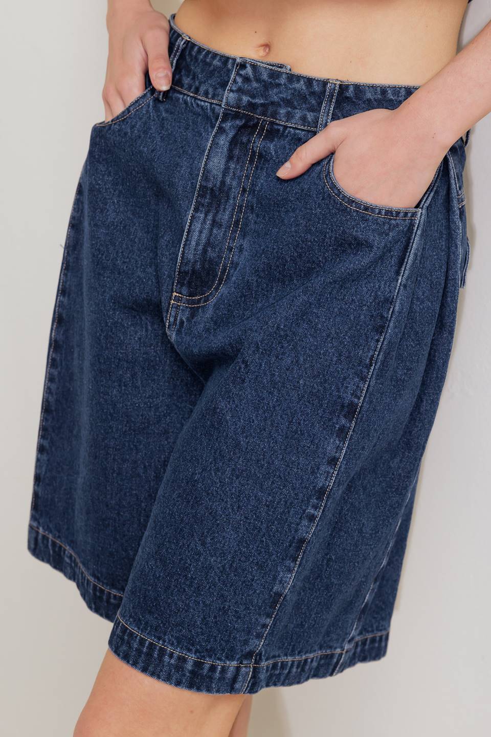 A washed denim short featuring front closure and side/back pockets.