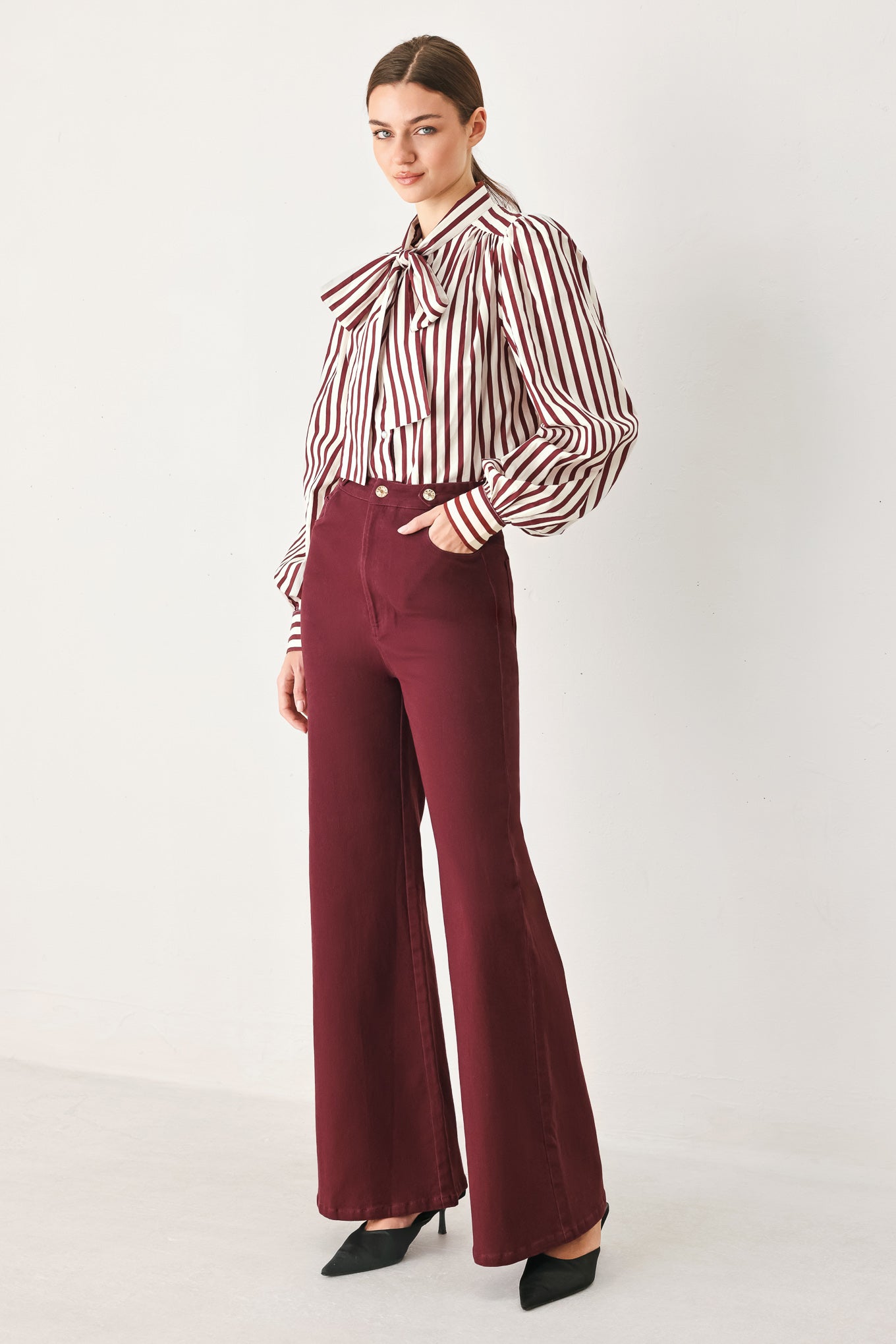 A woman wearing high-waisted burgundy wide-leg trouser pants with front closure and pockets | FREEMARKET