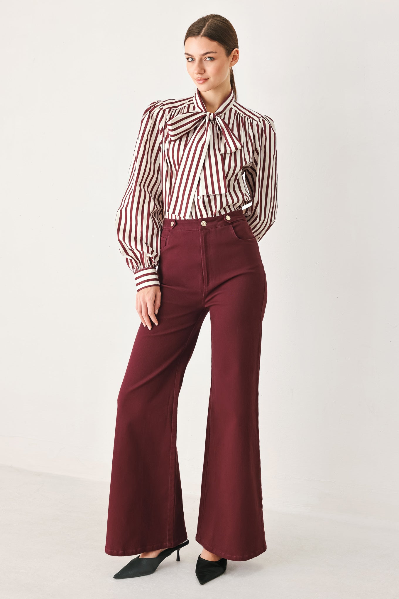A woman wearing high-waisted burgundy wide-leg trouser pants with front closure and pockets | FREEMARKET