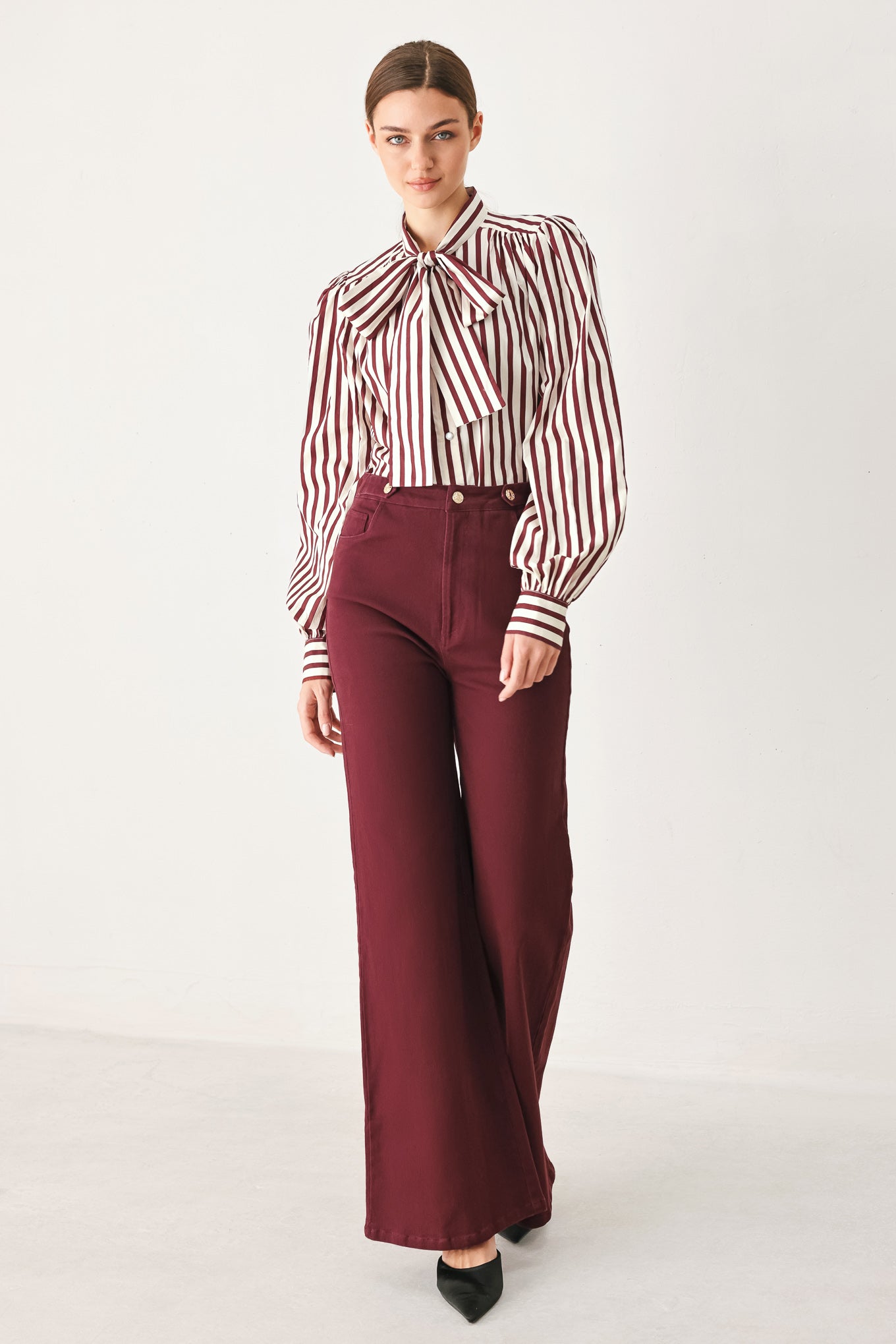 A woman wearing high-waisted burgundy wide-leg trouser pants with front closure and pockets | FREEMARKET