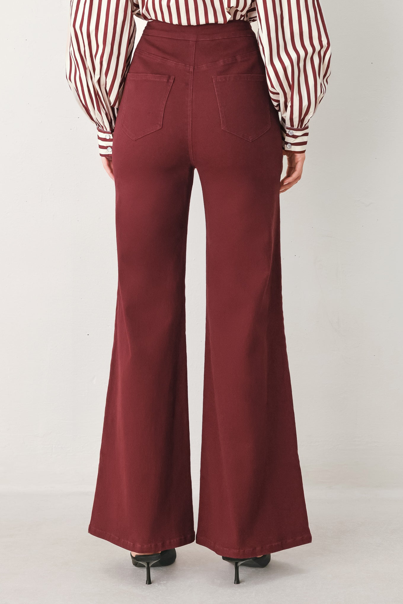 A woman wearing high-waisted burgundy wide-leg trouser pants with front closure and pockets | FREEMARKET