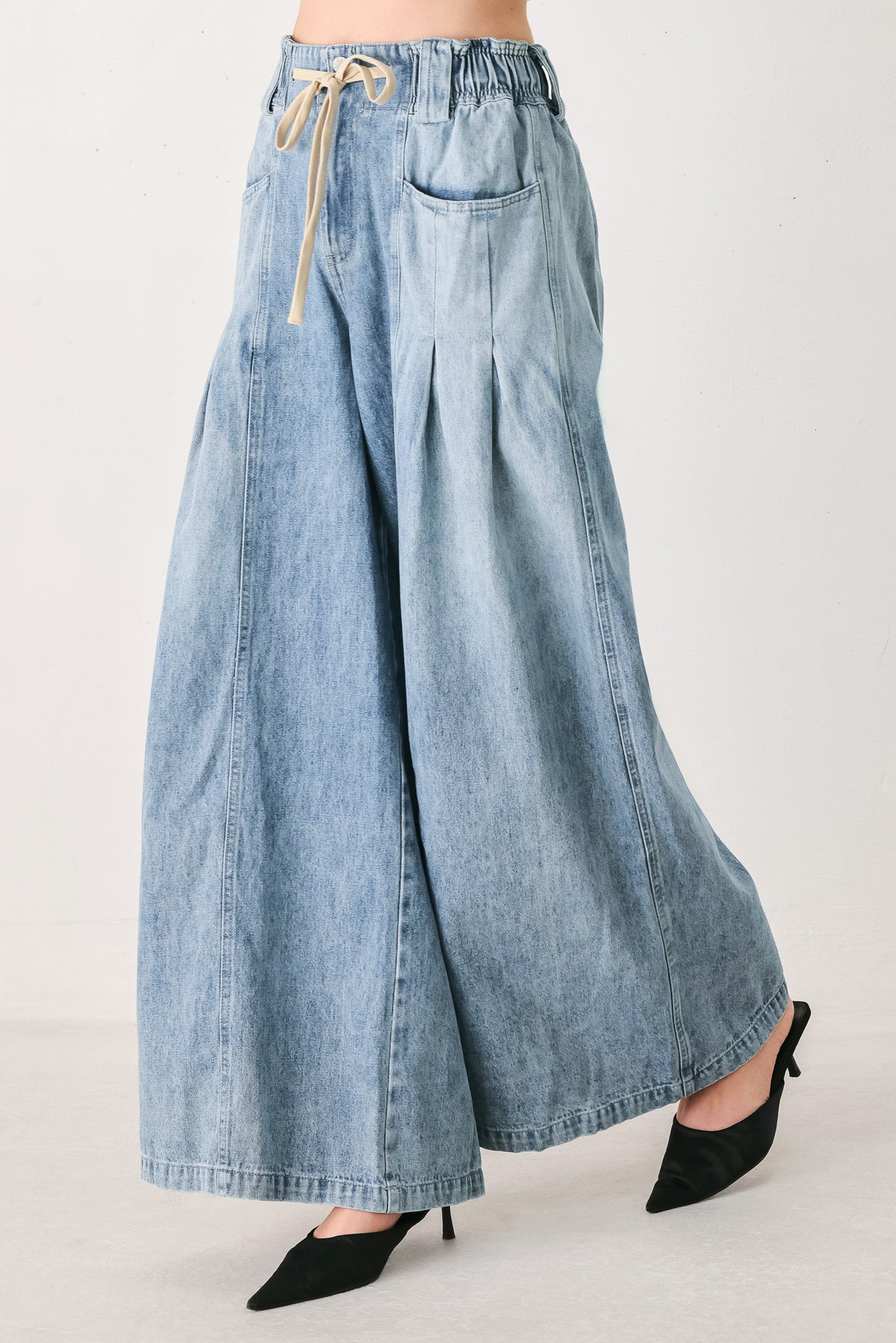 Light blue wide-leg denim pants with pleated front panels, side pockets, and a cream drawstring waist, shown on a model | FREEMARKET