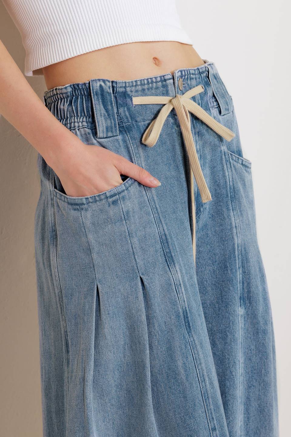 A washed denim pant featuring front closure, elasticized waist with contrasting tie, side pocket and wide leg