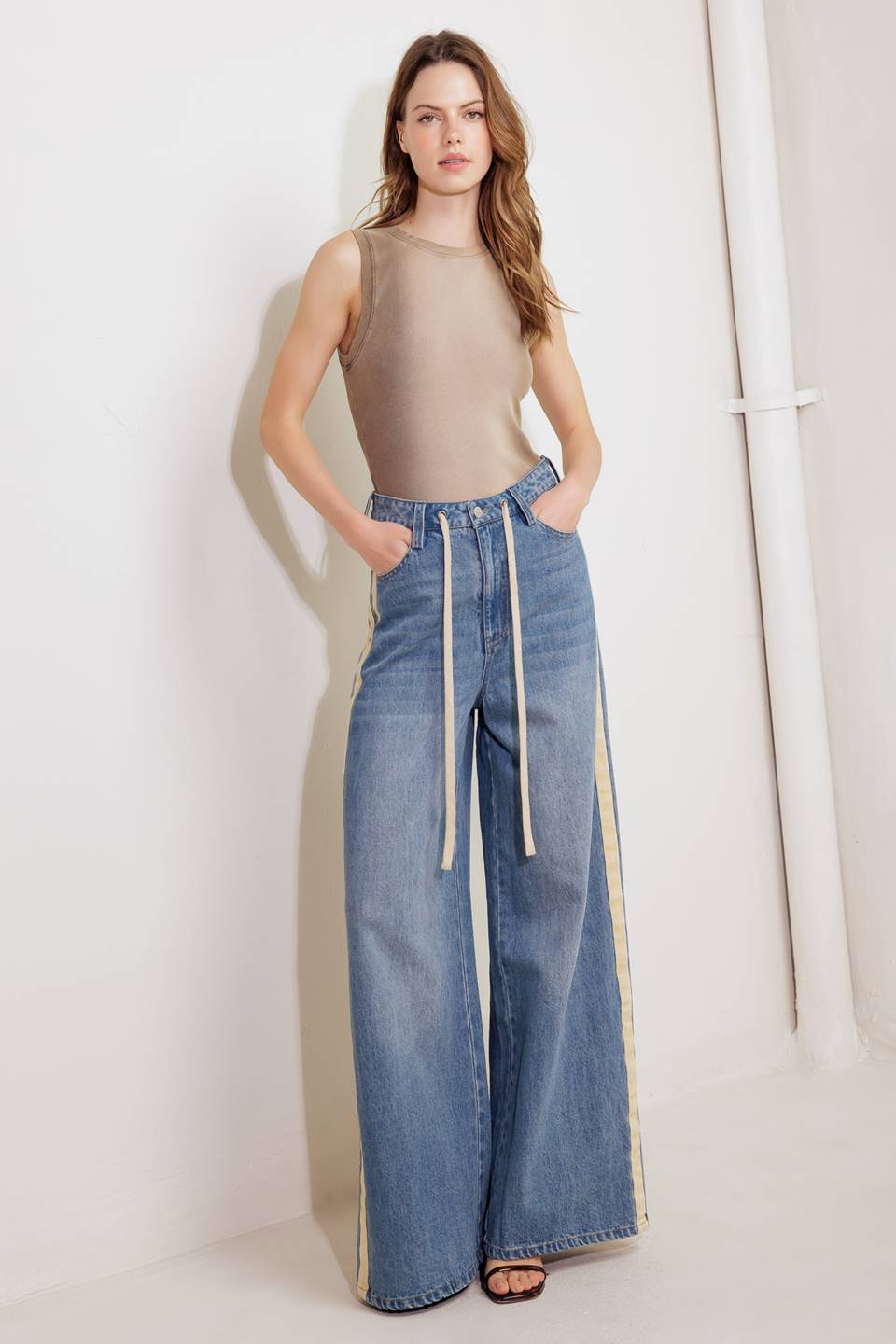 A washed denim pant featuring front closure, pockets, contrasting waist tie, side contrasting stripe and wide leg