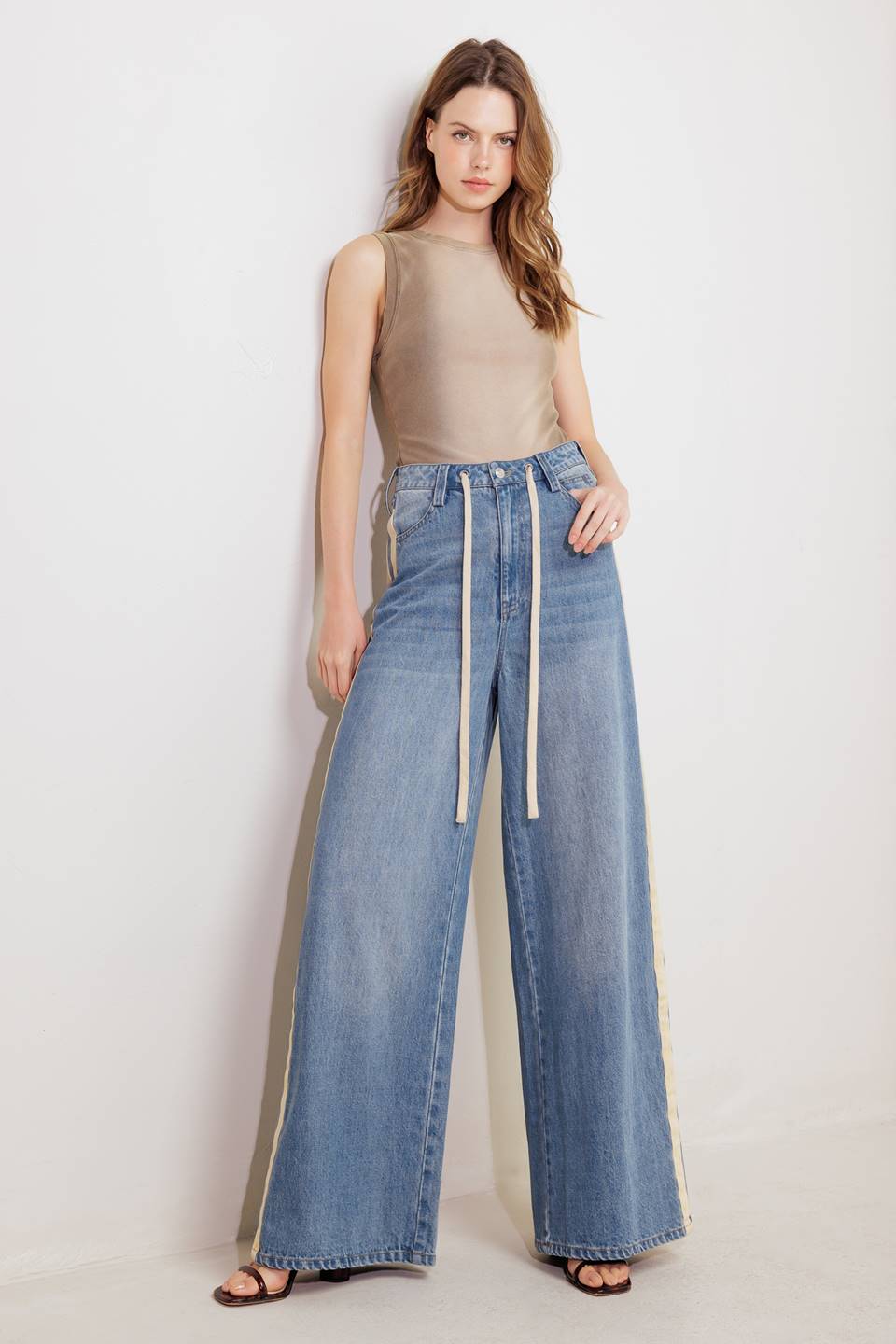 A washed denim pant featuring front closure, pockets, contrasting waist tie, side contrasting stripe and wide leg