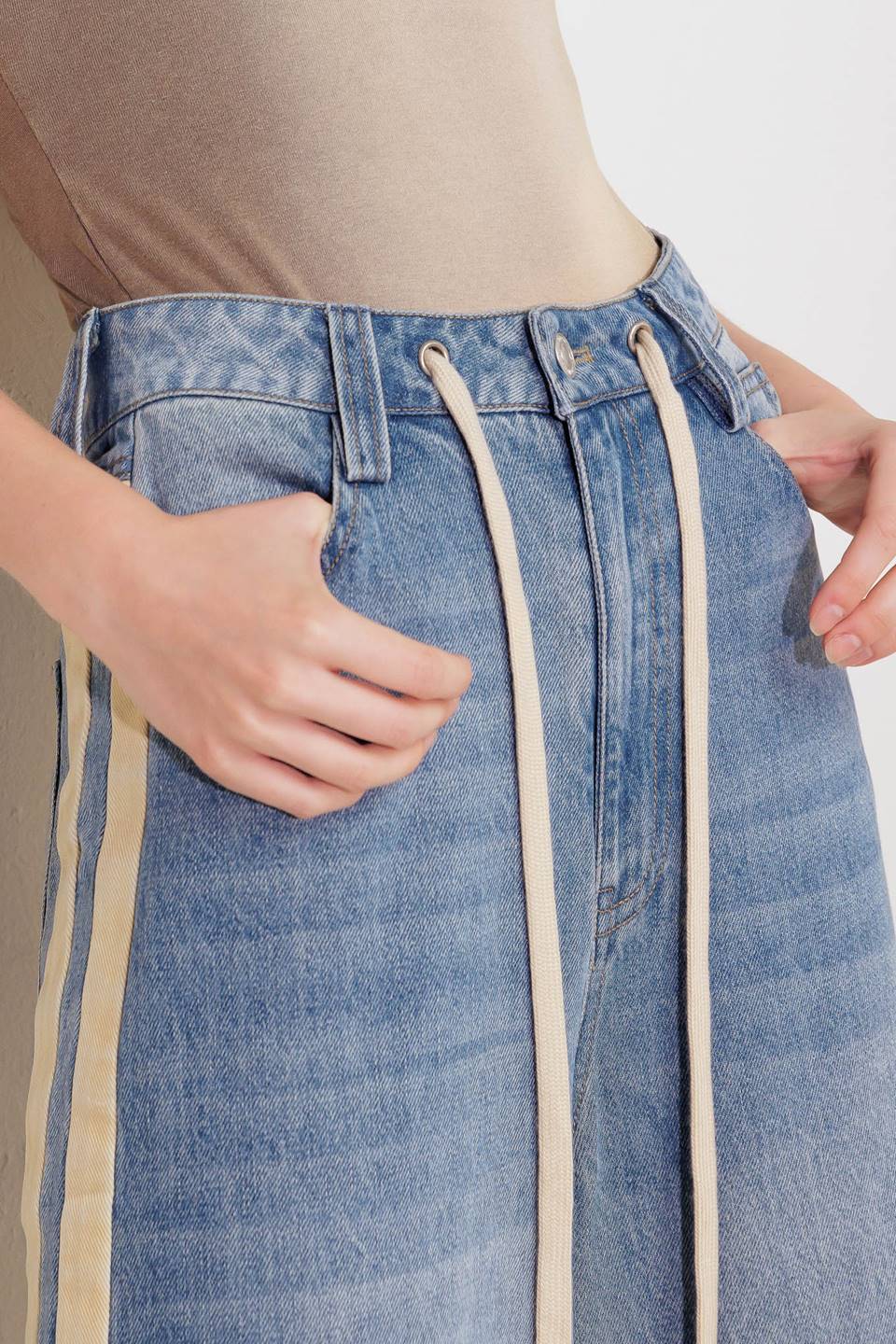 A washed denim pant featuring front closure, pockets, contrasting waist tie, side contrasting stripe and wide leg