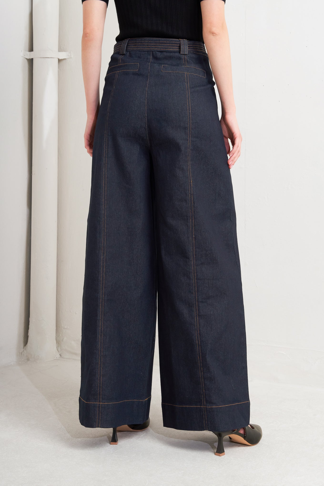 A denim pant featuring front closure, side pockets, self belt and wide
