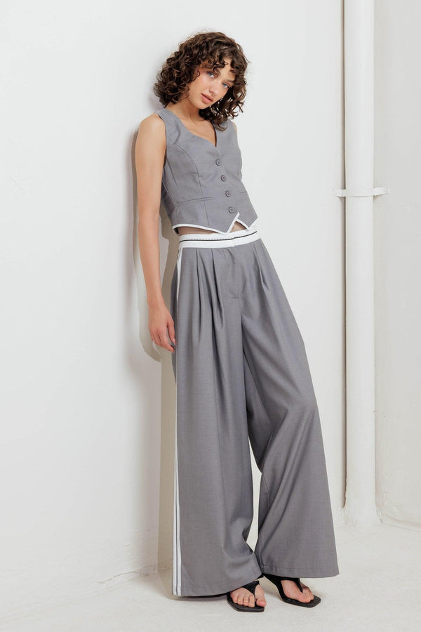 A solid woven pant featuring front closure, side pockets, contrasting waistband and side stripes and wide leg. 