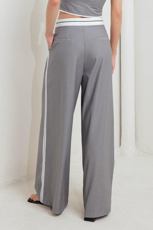 A solid woven pant featuring front closure, side pockets, contrasting waistband and side stripes and wide leg. 