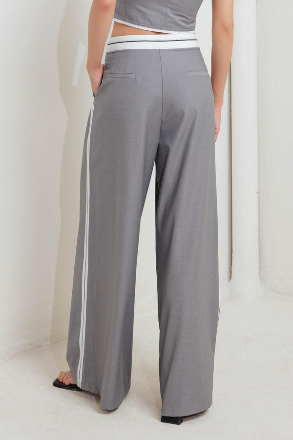 A solid woven pant featuring front closure, side pockets, contrasting waistband and side stripes and wide leg. 
