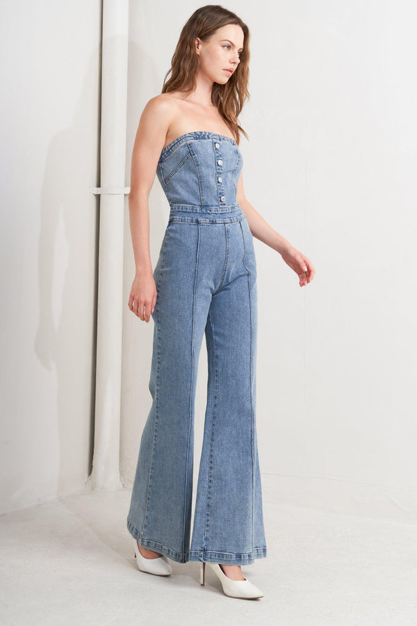 A washed denim jumpsuit featuring strapless, front button detail, wide leg and back zipper closure