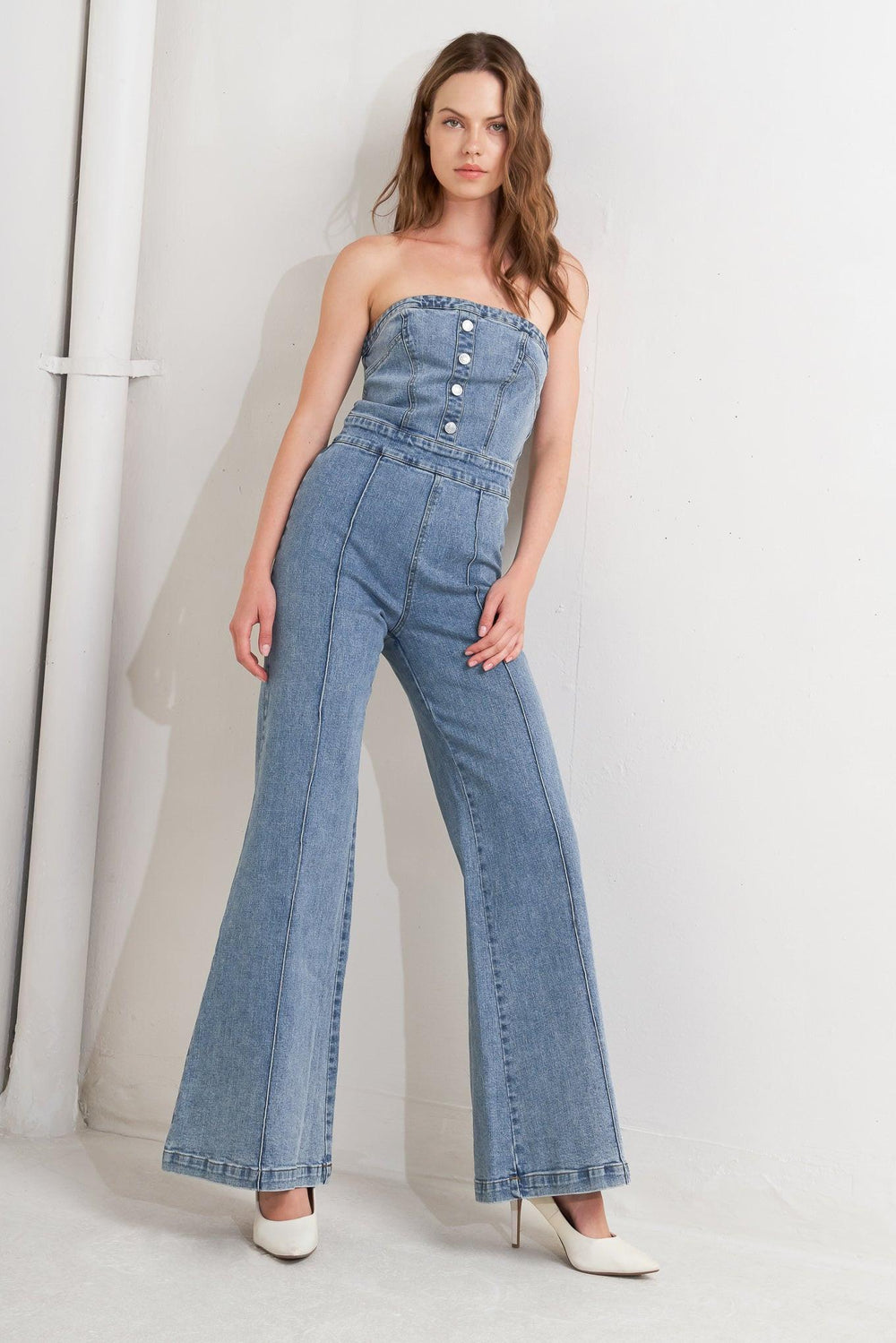 A washed denim jumpsuit featuring strapless, front button detail, wide leg and back zipper closure