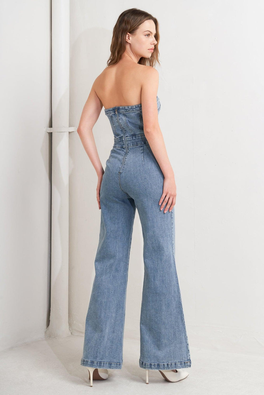 A washed denim jumpsuit featuring strapless, front button detail, wide leg and back zipper closure