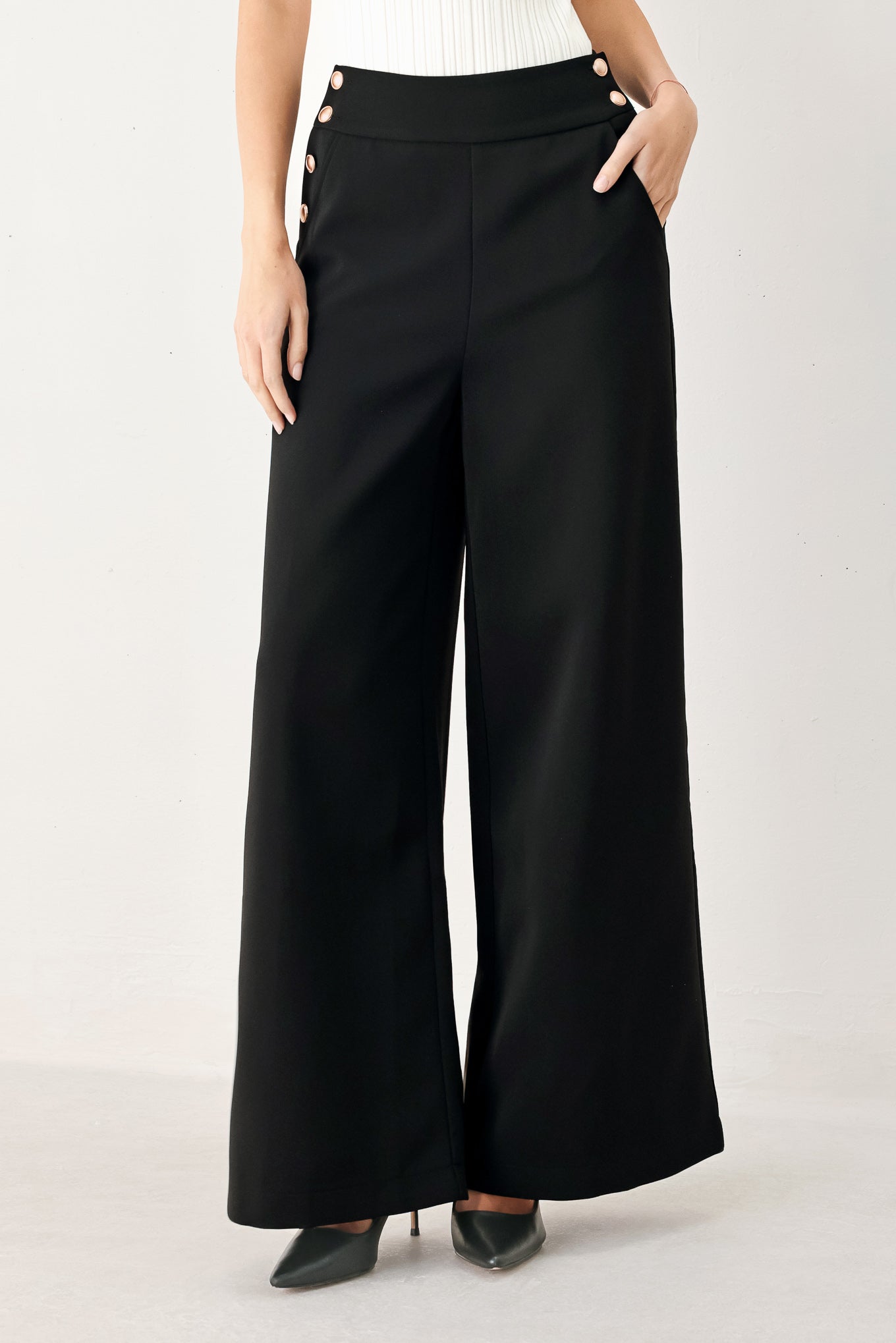 Woman wearing black wide-leg pants with gold button detail | FREEMARKET