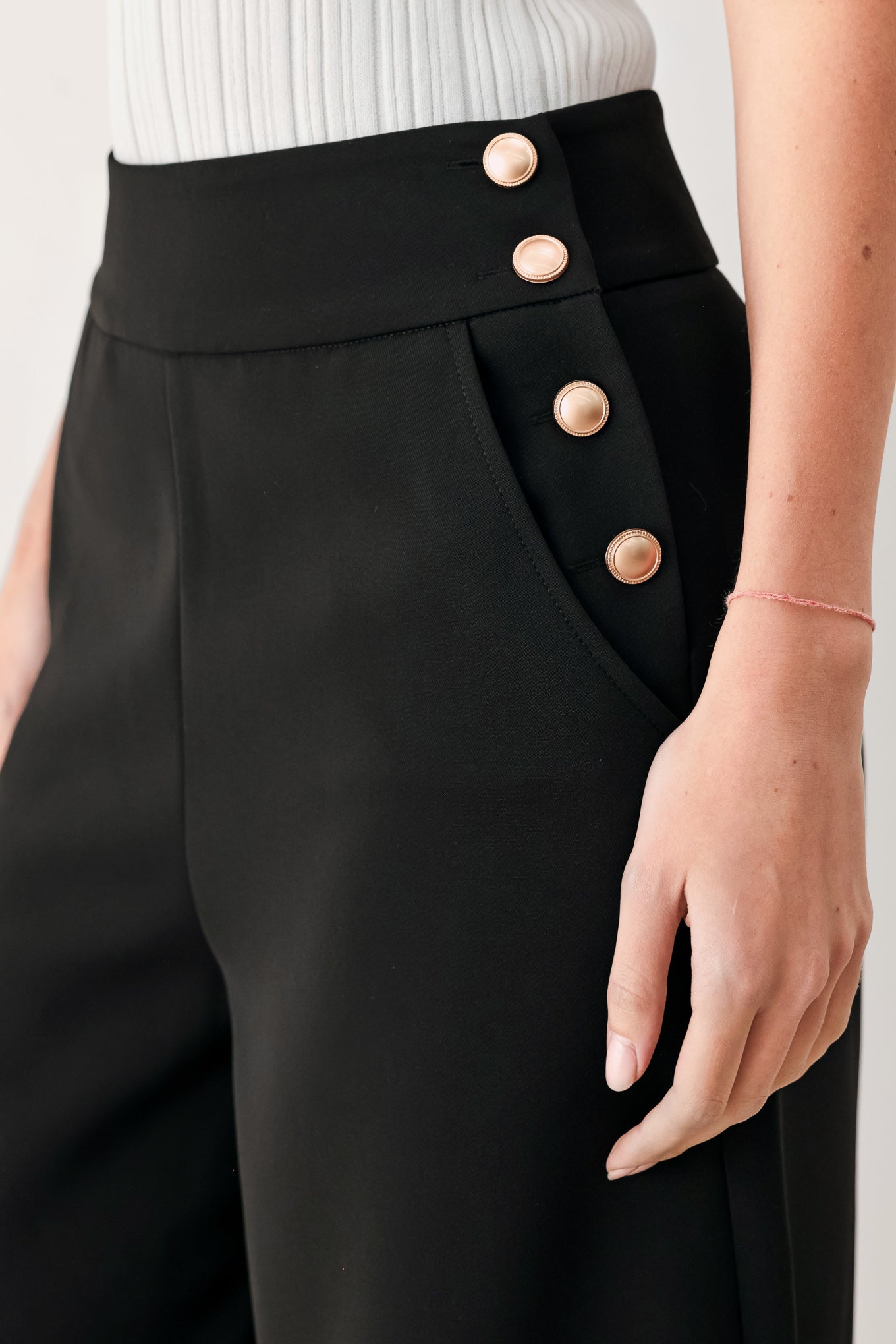 Woman wearing black wide-leg pants with gold button detail | FREEMARKET