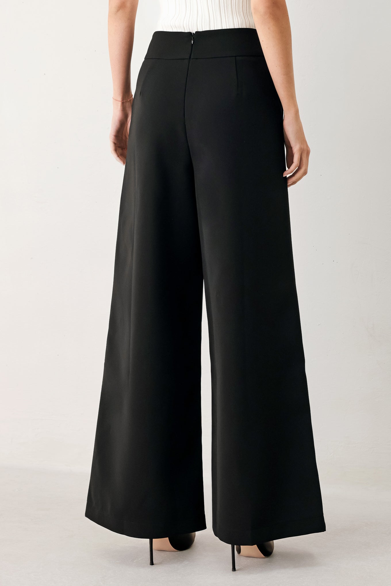 Woman wearing black wide-leg pants with gold button detail | FREEMARKET