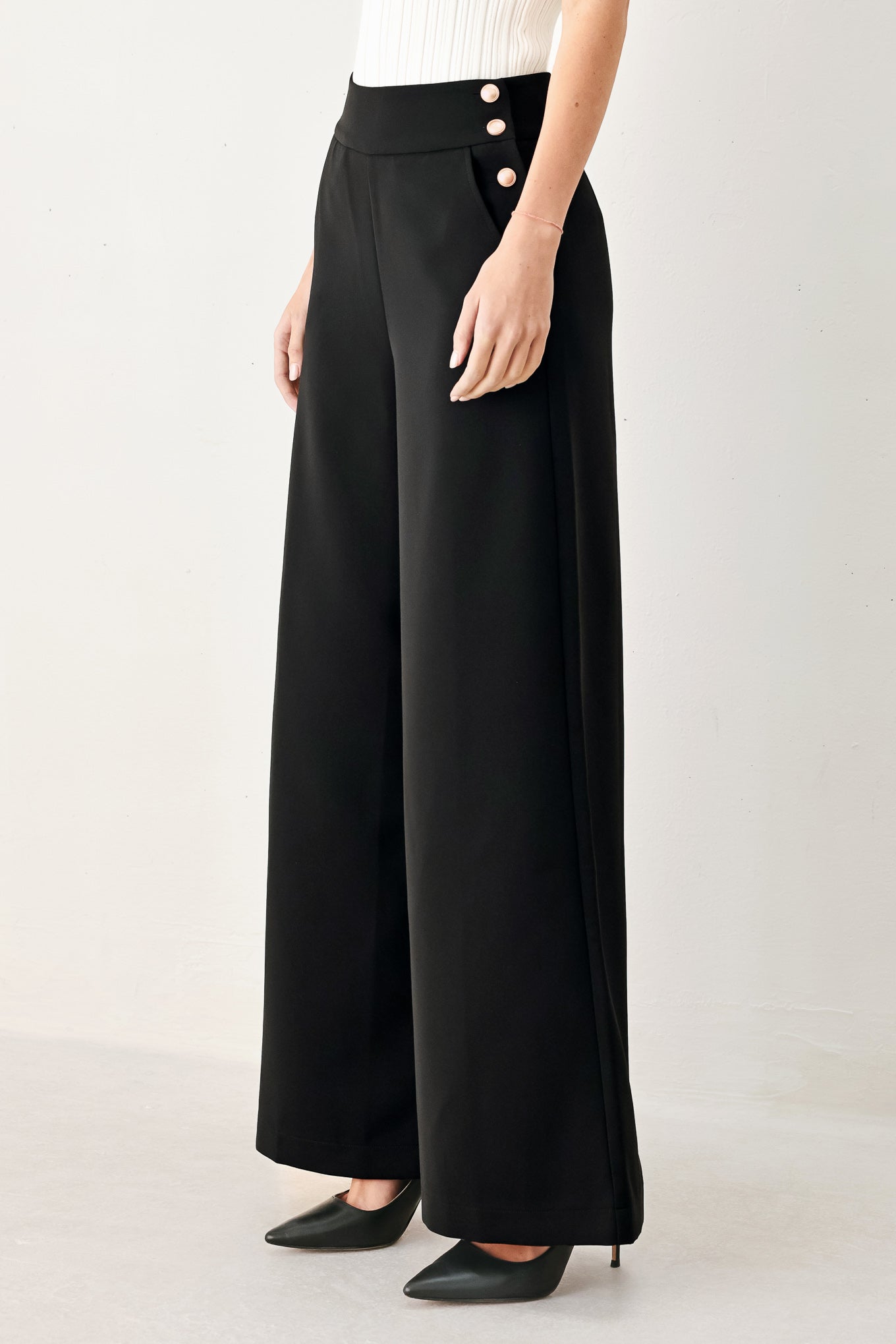 Woman wearing black wide-leg pants with gold button detail | FREEMARKET