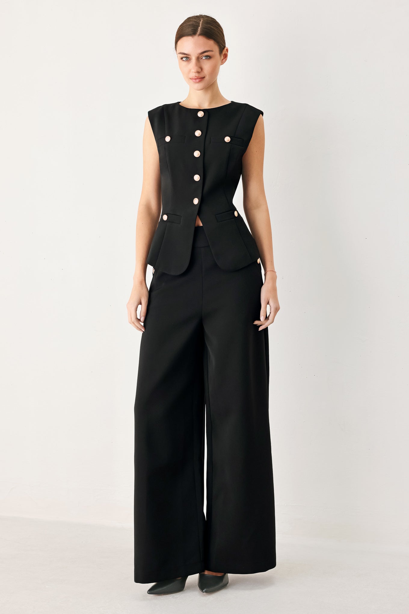 Woman wearing black wide-leg pants with gold button detail | FREEMARKET