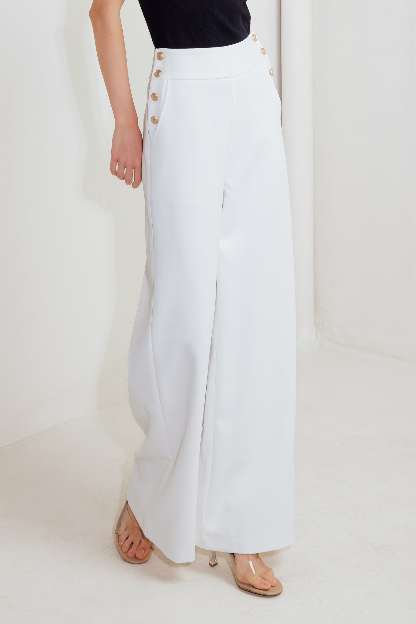 Woman wearing white wide-leg pants with gold button detail | FREEMARKET