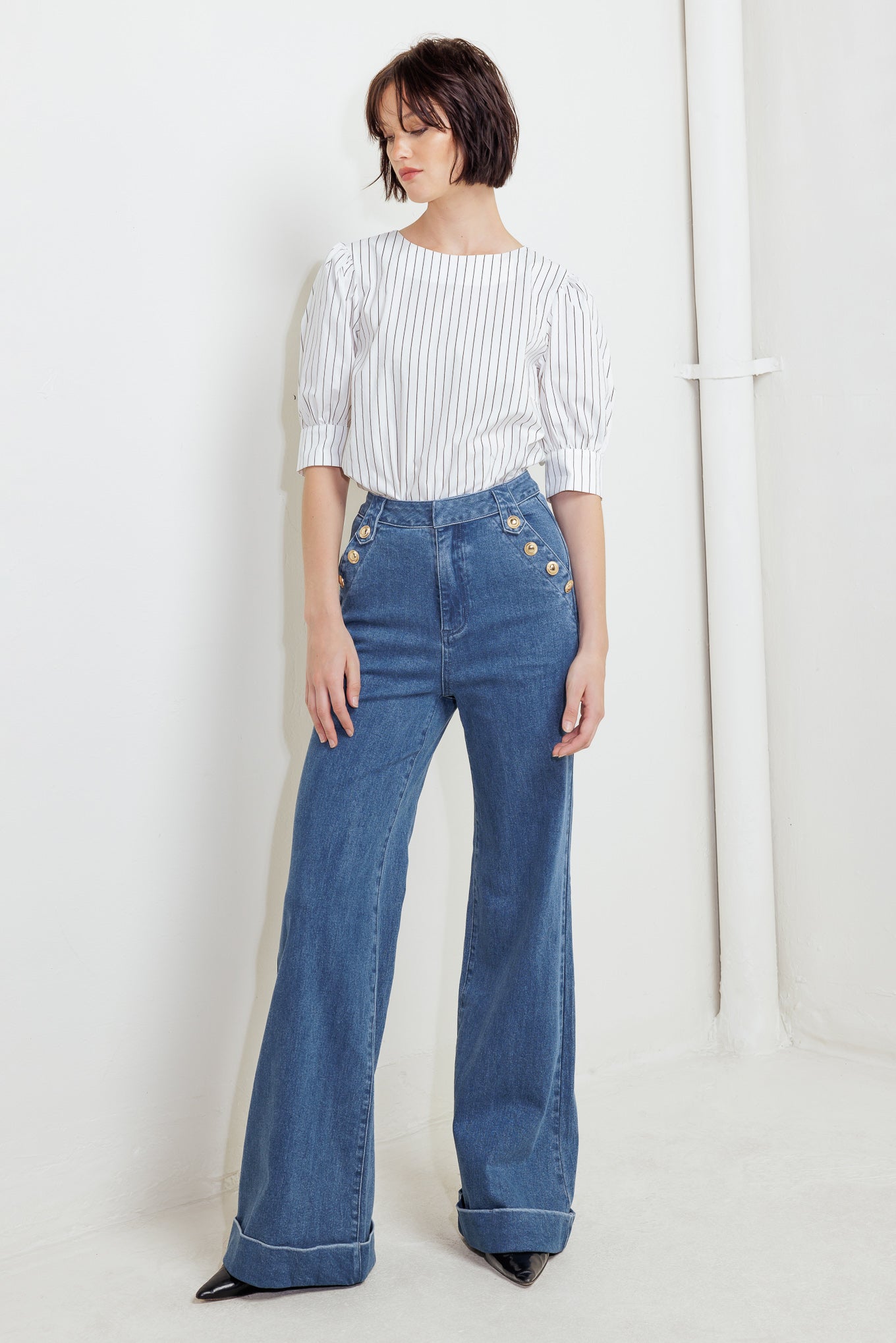A washed denim pant featuring front closure, side pocket with button detail and wide leg with cuffed hem
