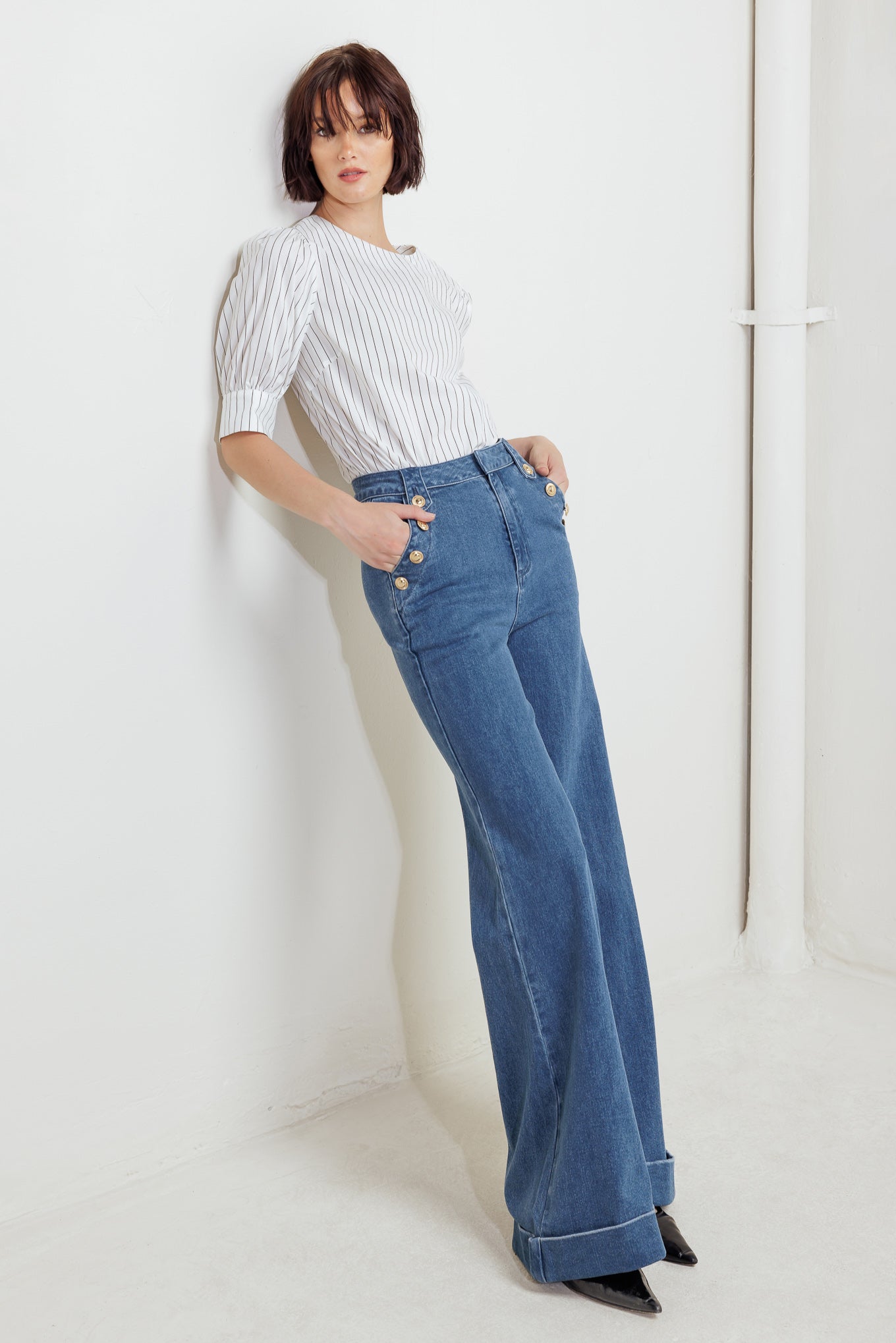 A washed denim pant featuring front closure, side pocket with button detail and wide leg with cuffed hem