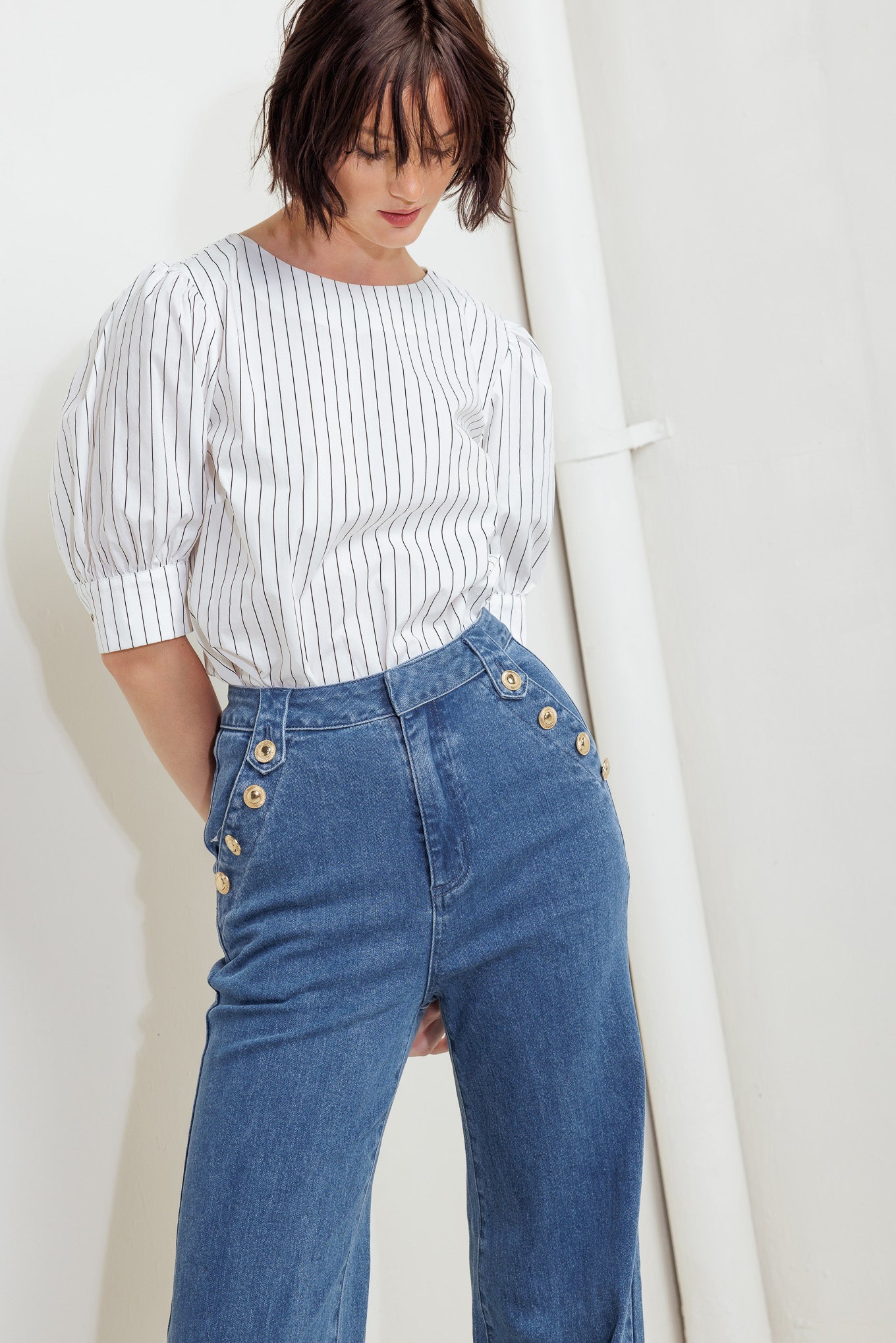 A washed denim pant featuring front closure, side pocket with button detail and wide leg with cuffed hem