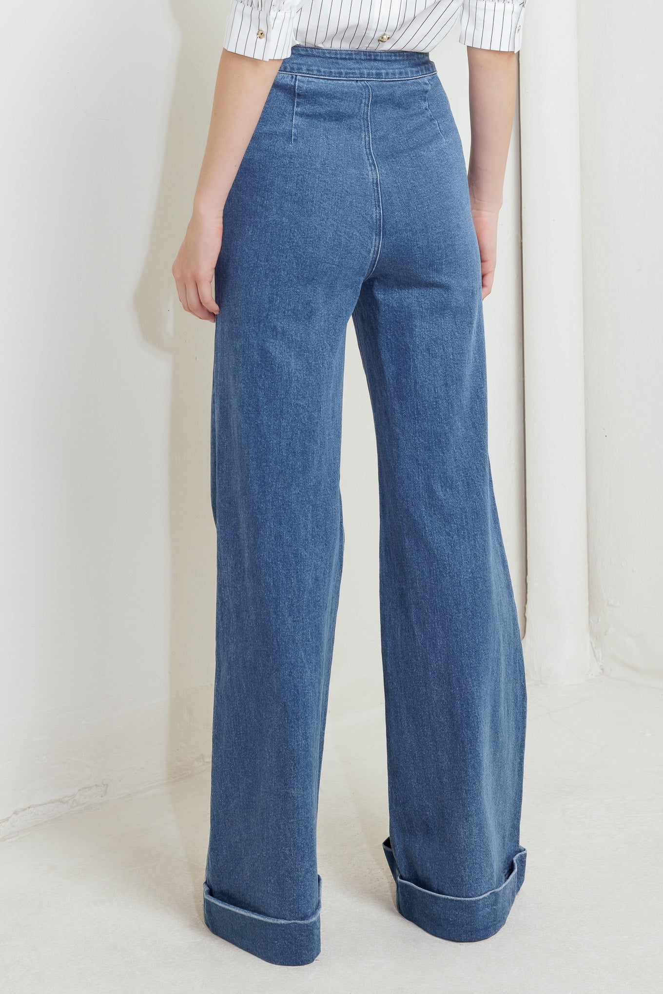 A washed denim pant featuring front closure, side pocket with button detail and wide leg with cuffed hem