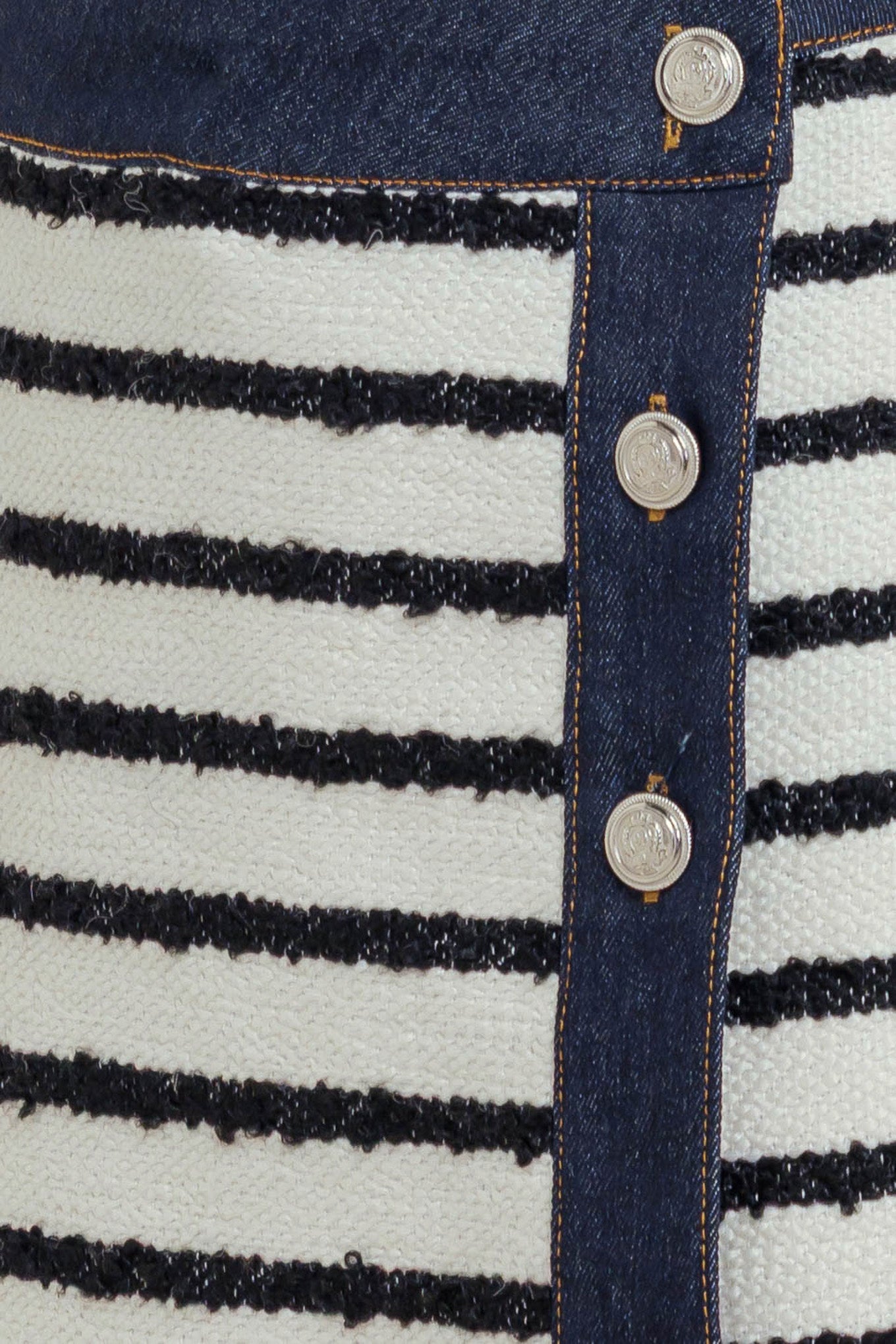 A textured striped woven skort featuring front button detail and denim trimmed edge.