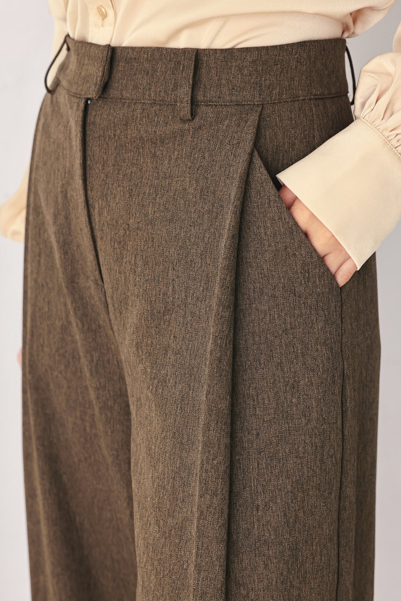 A woman wearing high-waisted, wide-leg brown trousers | FREEMARKET