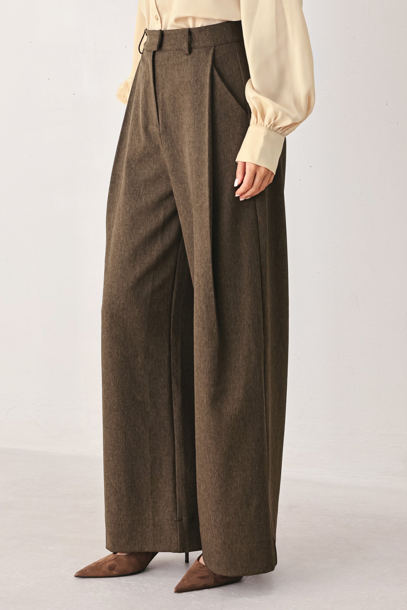 A woman wearing high-waisted, wide-leg brown trousers | FREEMARKET