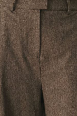 A woman wearing high-waisted, wide-leg brown trousers | FREEMARKET