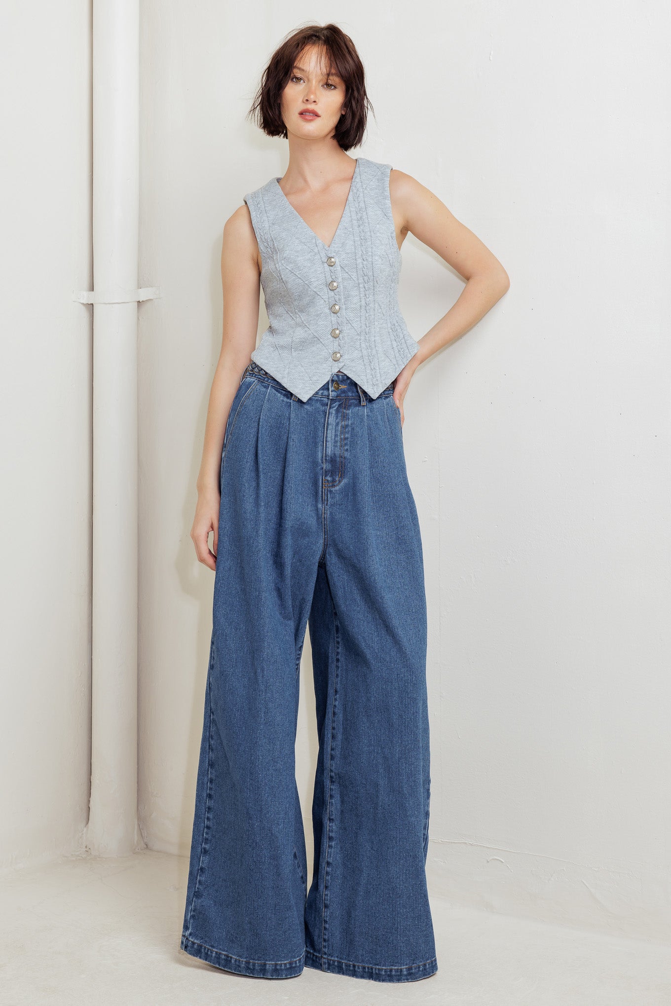 A washed denim pant featuring braided waistband, front closure, side pockets and wide leg