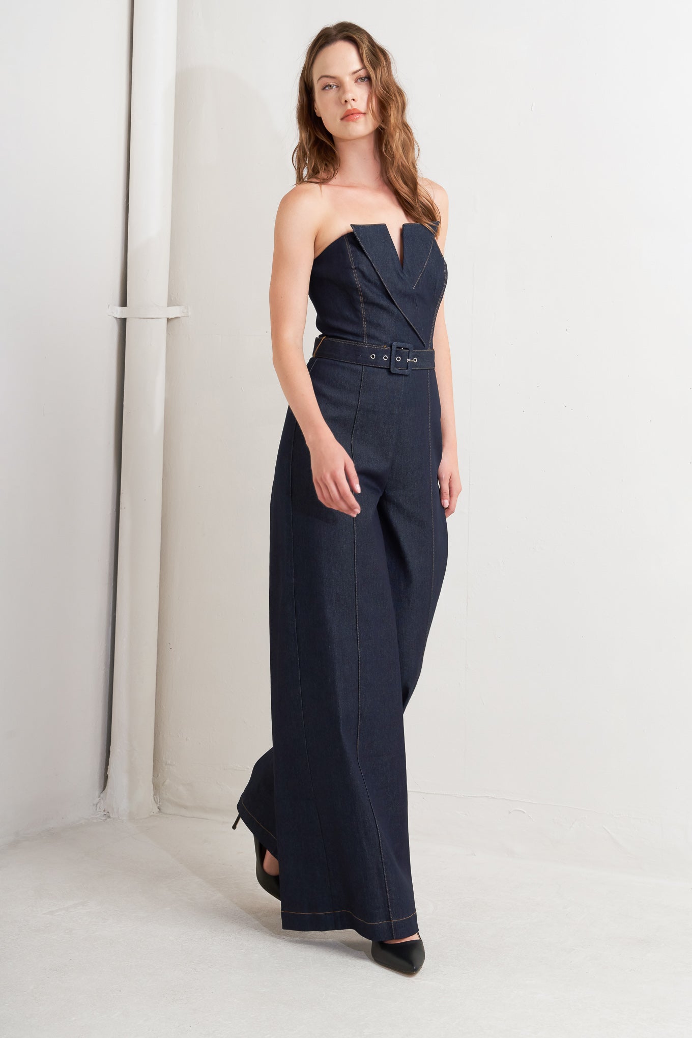 A denim jumpsuit featuring strapless, front fold over detail, self belt and wide leg