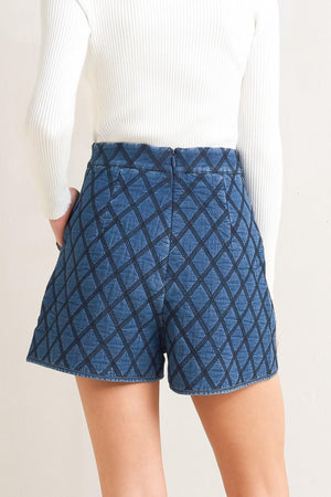 A quilted woven short featuring side pocket with button detail and back zipper closure.