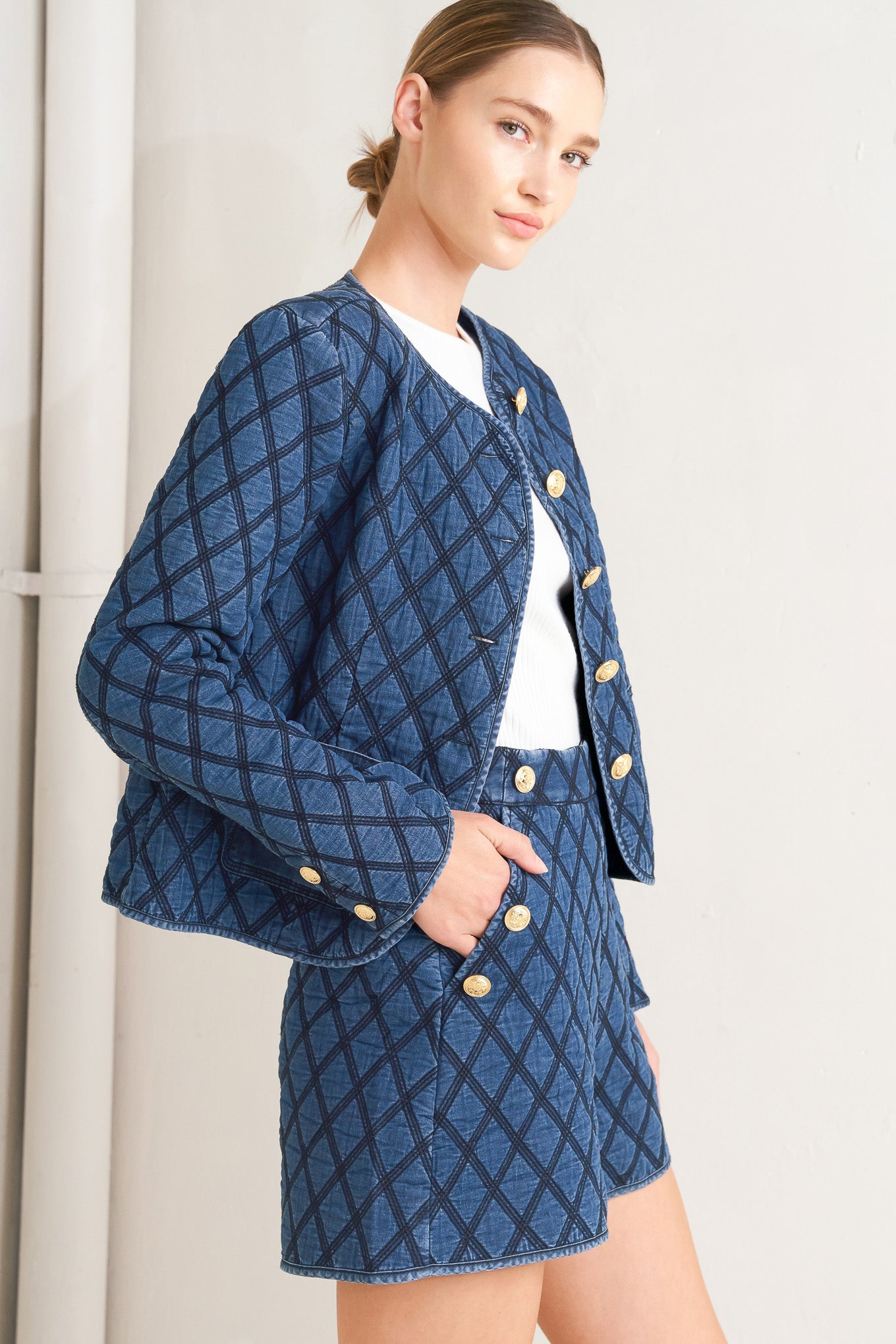 A quilted woven short featuring side pocket with button detail and back zipper closure.