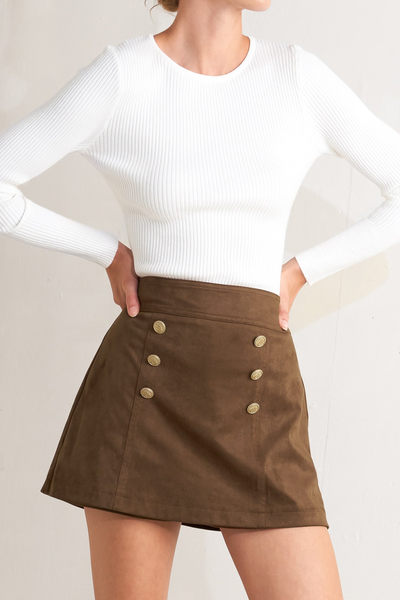 A faux suede skort with front button detail and back zipper closure.