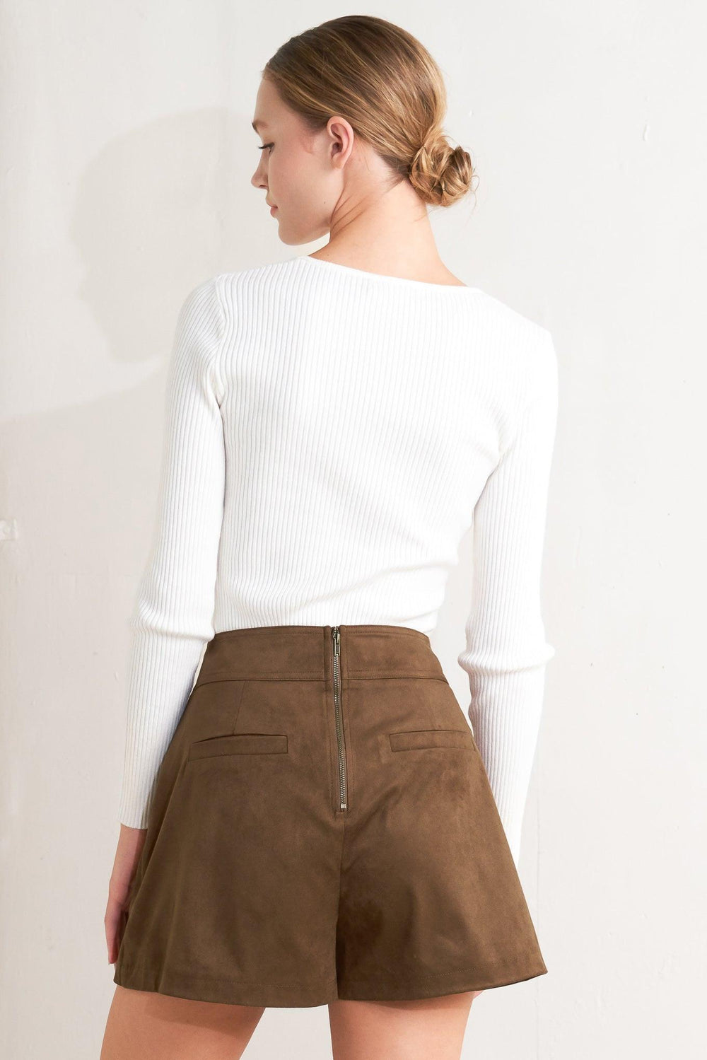 A faux suede skort with front button detail and back zipper closure.