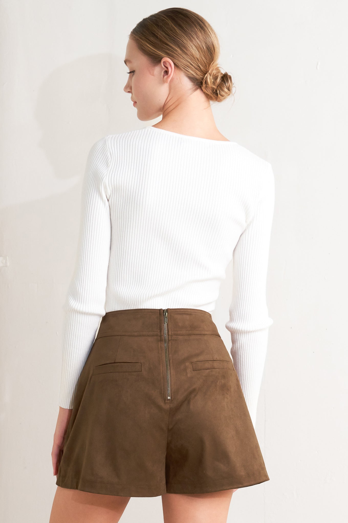 A faux suede skort with front button detail and back zipper closure.