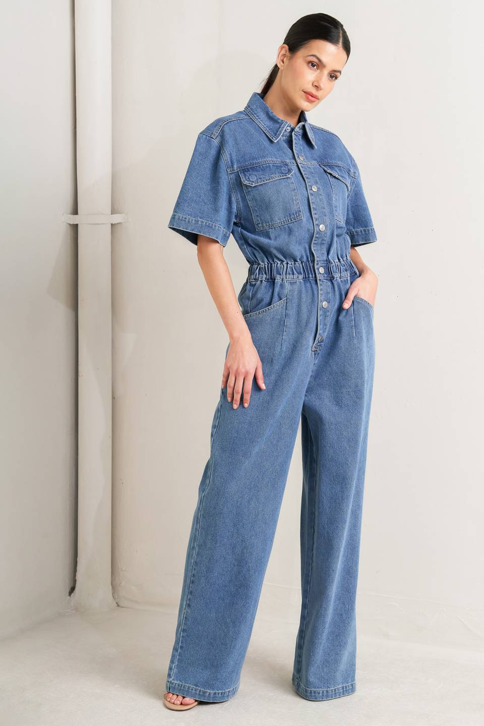 Woman wearing a denim jumpsuit against a plain background - FLYING TOMATO