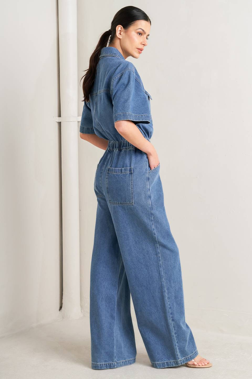 Woman wearing a denim jumpsuit against a plain background - FLYING TOMATO
