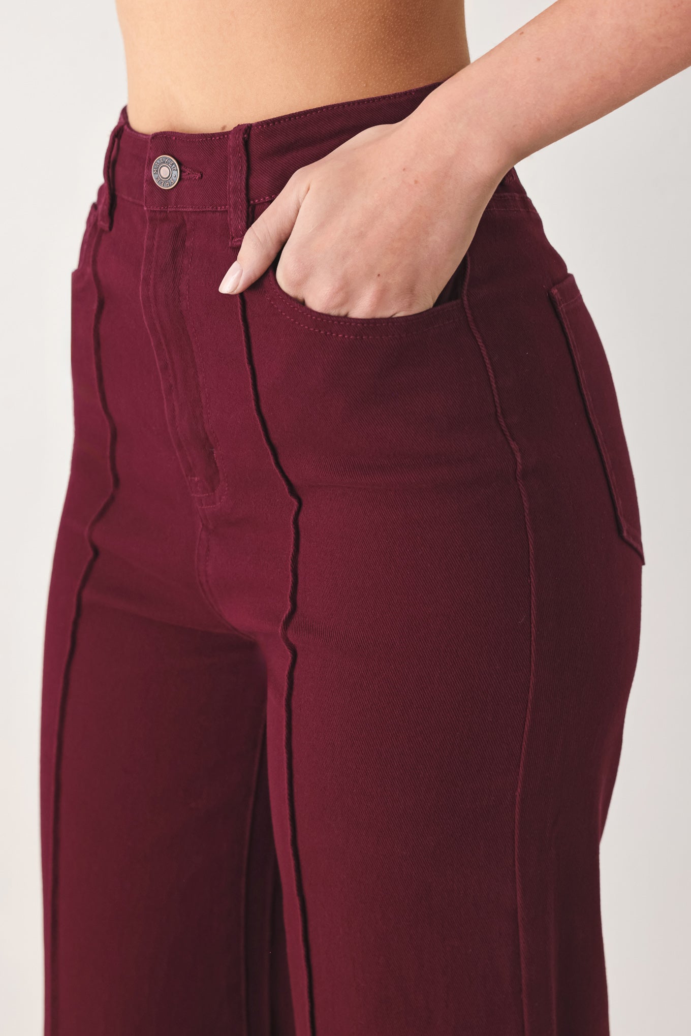 Woman wearing solid burgundy twill pants featuring front closure, front seam in the middle of each leg and pockets | FREEMARKET