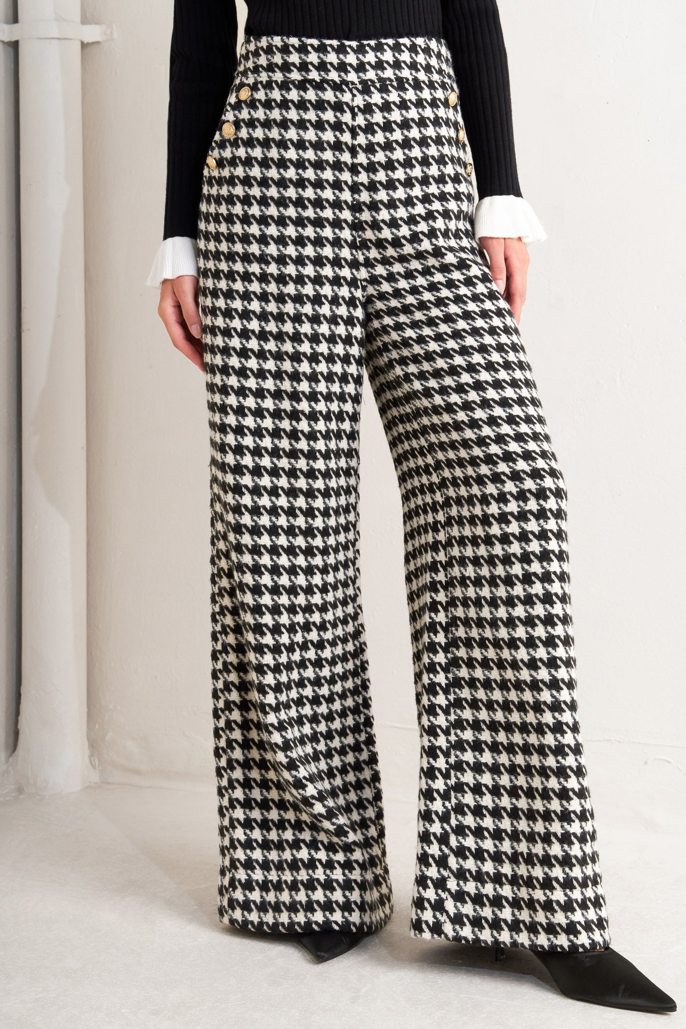 A woven houndstooth wide leg pant with side pockets with buttons and back zipper closure. 