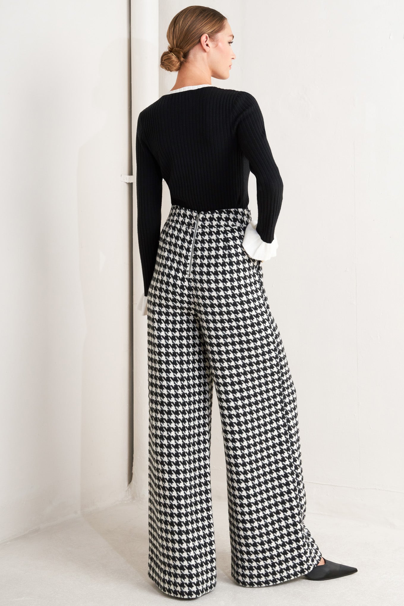 A woven houndstooth wide leg pant with side pockets with buttons and back zipper closure. 
