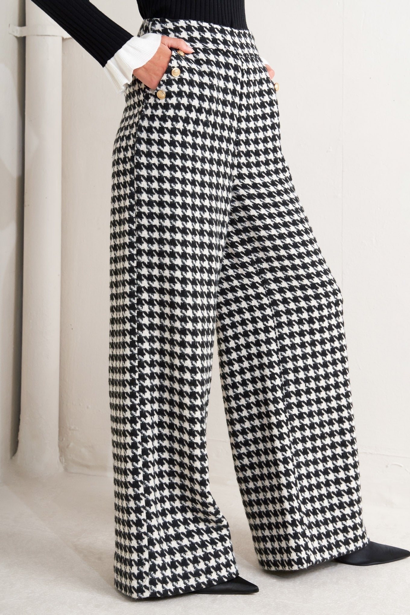 A woven houndstooth wide leg pant with side pockets with buttons and back zipper closure. 