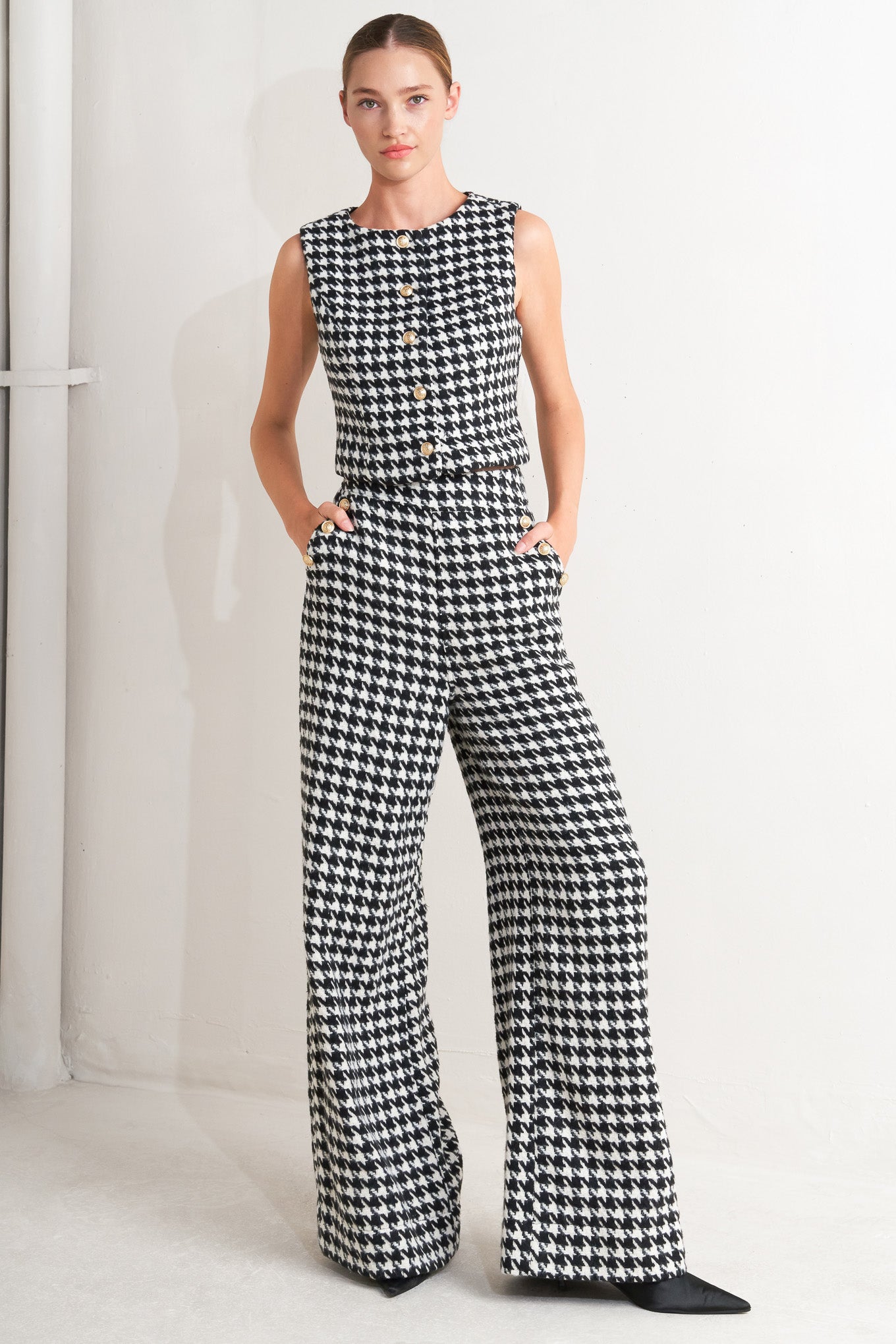 A woven houndstooth wide leg pant with side pockets with buttons and back zipper closure. 