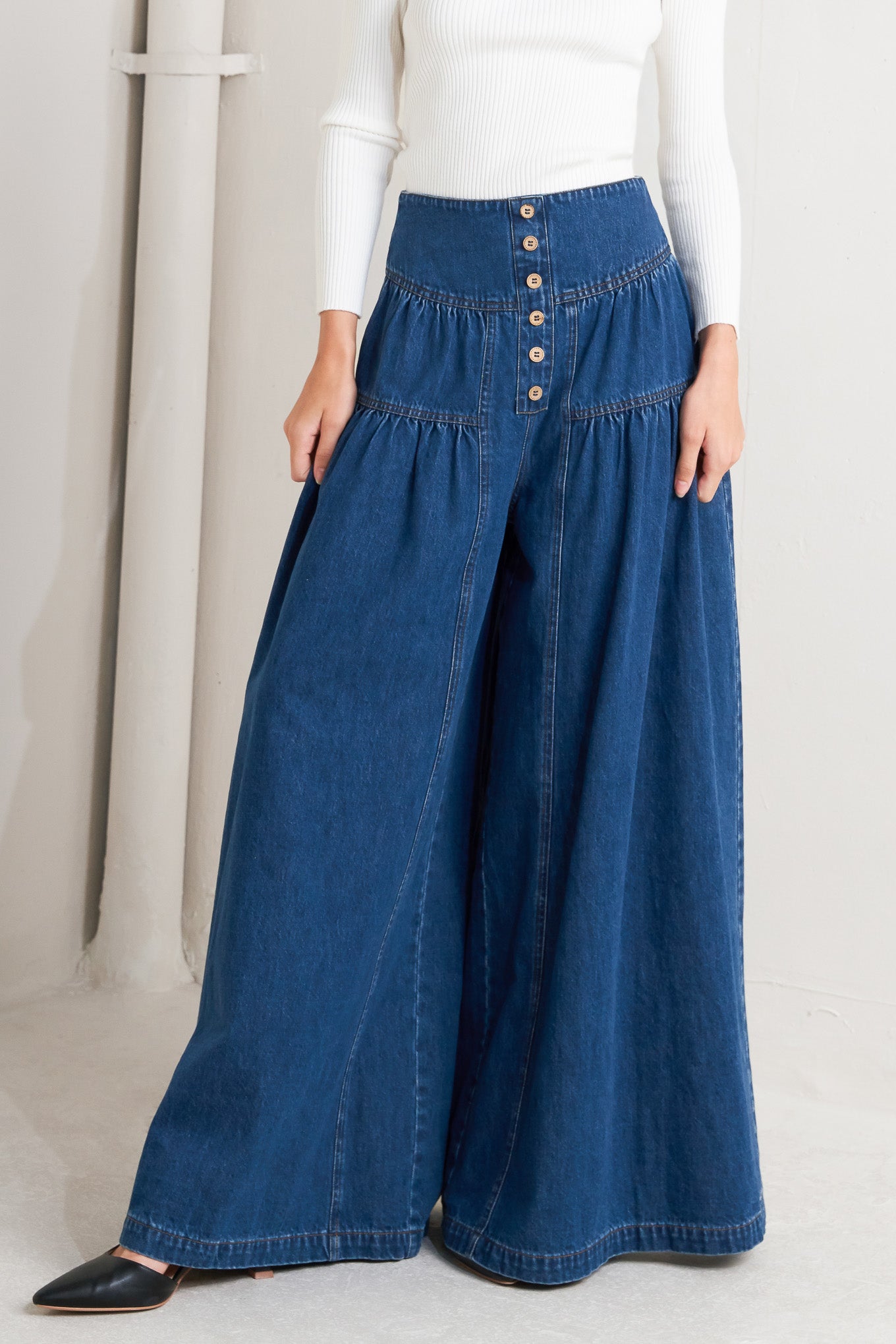 A washed denim pant with front button detail, shirring and back zipper closure