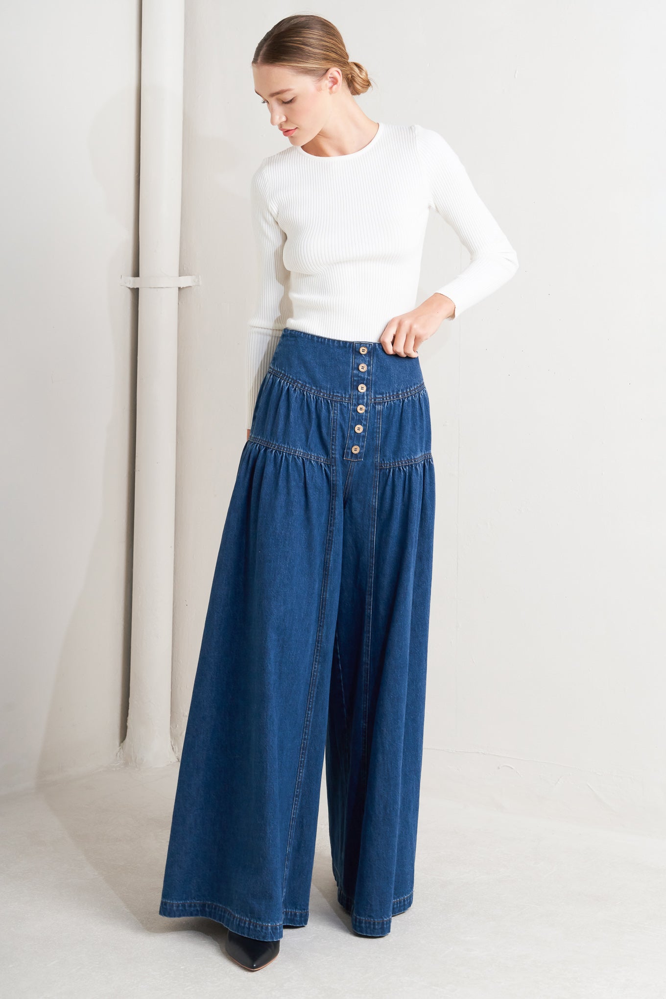 A washed denim pant with front button detail, shirring and back zipper closure
