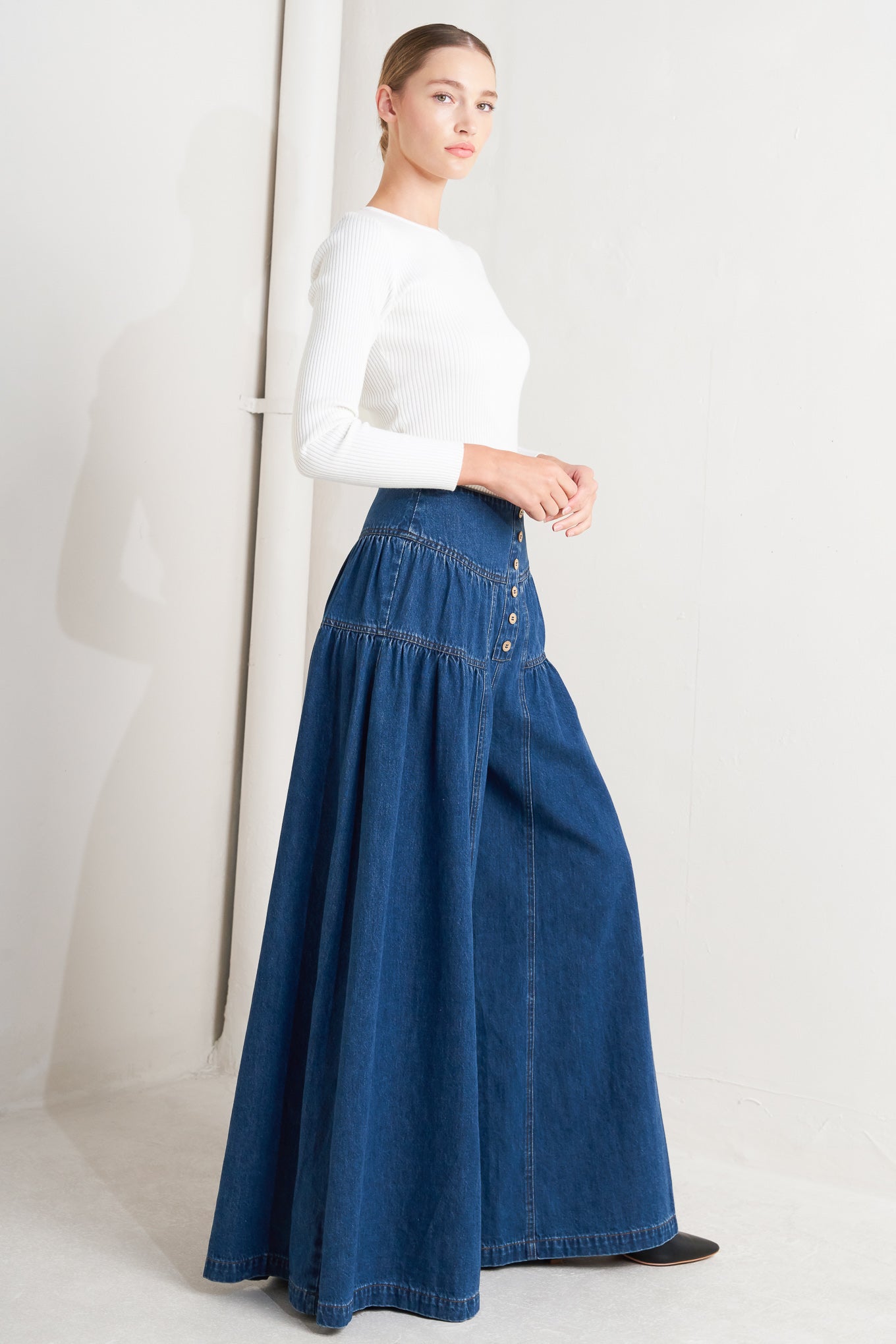 A washed denim pant with front button detail, shirring and back zipper closure