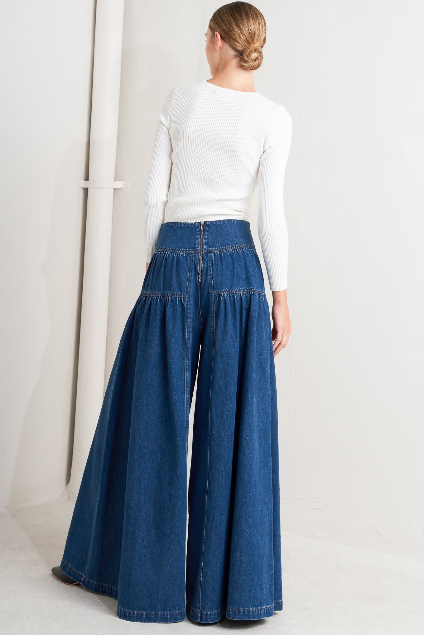 A washed denim pant with front button detail, shirring and back zipper closure